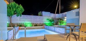 A swimming pool with a wooden deck, a tree, and a wall with a textured pattern. - Stay Helios (Rhodes)