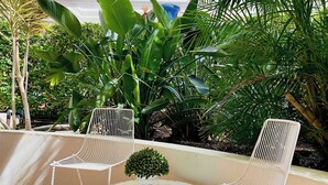 A terrace with two white wire-framed chairs, a small round table, and a potted plant. - The Phoenician Luxe Suite (Broadbeach)