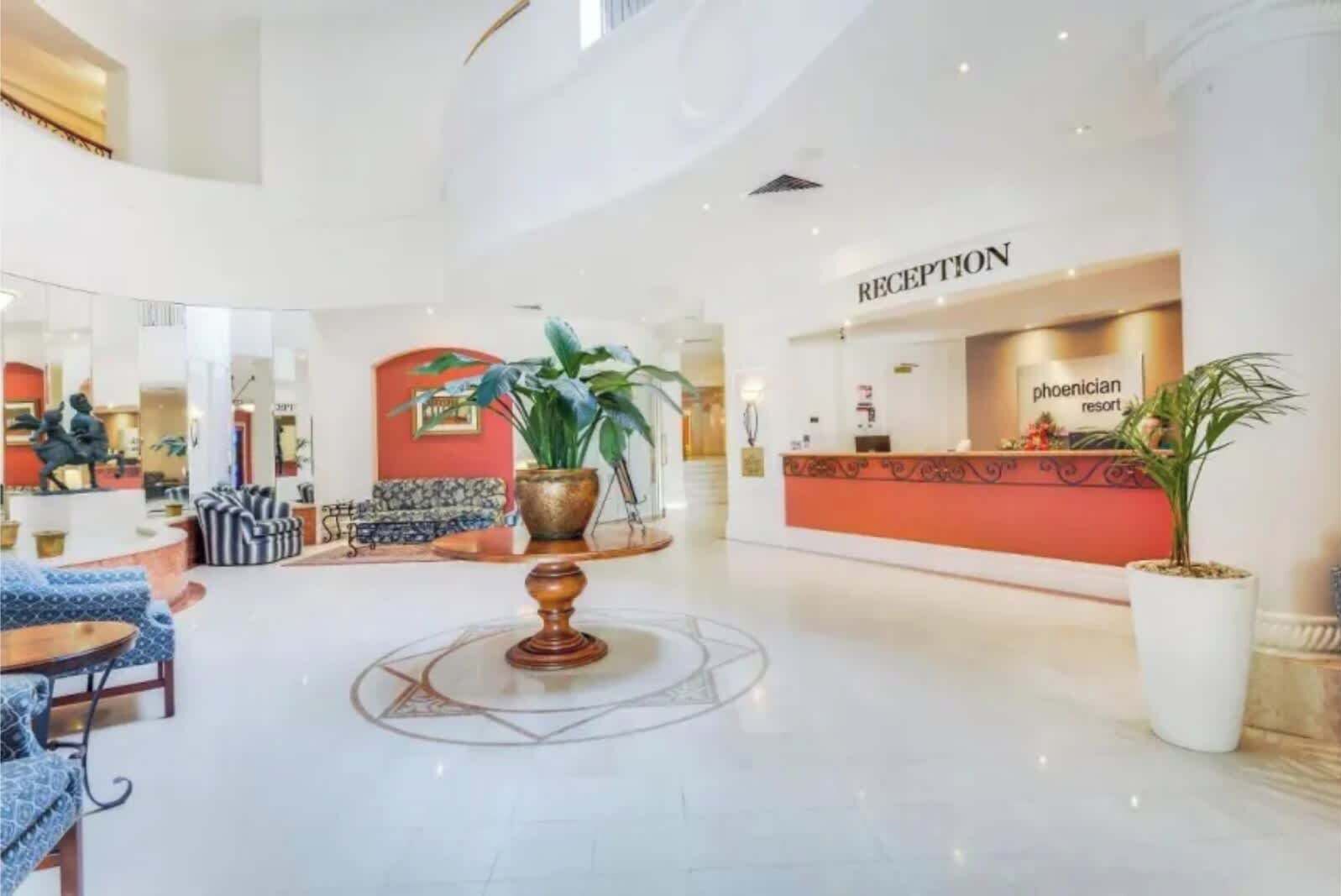 Una hall d'albergo con reception, zone relax e un elemento decorativo centrale.