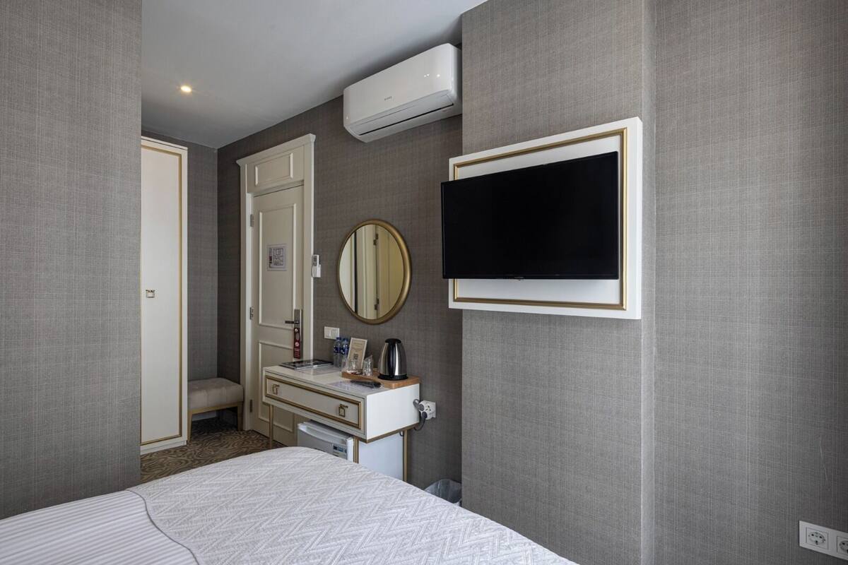 Ein Hotelzimmer mit Bett, Schminktisch, Spiegel, Fernseher und Klimaanlage.