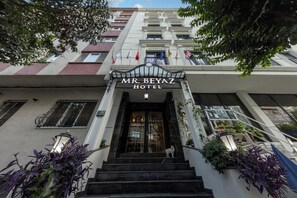 The entrance of the MR BEYAZ HOTEL with a staircase leading up to the doors, surrounded by potted plants and flags. - MR. Beyaz Boutique Hotel (Istanbul)