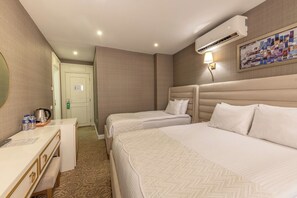 Une chambre d’hôtel avec deux lits, un bureau avec un miroir, un climatiseur fixé au mur et un tableau.
