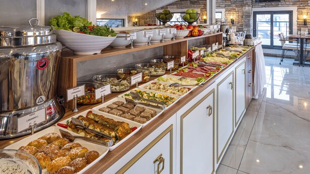 Un bufé con diversas opciones de comida, como ensaladas, carnes y postres.