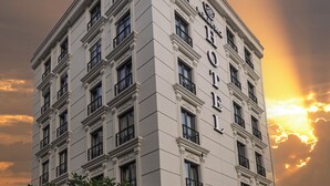 Un hotel de estilo arquitectónico clásico, con una entrada destacada y varios balcones.