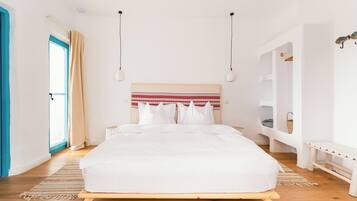 A bedroom with a bed, bedside tables, a window with curtains, and a built-in bench.