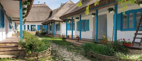 A traditional village setting with thatched-roof houses, a cobblestone pathway, and a rustic wooden fence.
