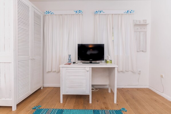 A white desk with a television, a small vase, and a remote control. - 5chirpici (Murighiol)