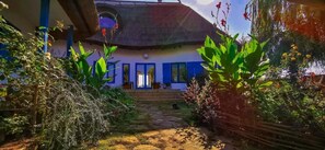 A house with a thatched roof, a blue door, and a garden with various plants. - 5chirpici (Murighiol)