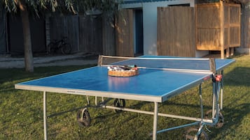 A ping pong table set up outdoors with a bicycle nearby.