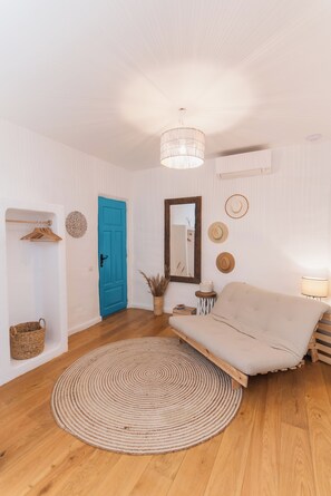 A room with a blue door, a round woven rug, a sofa, a mirror, and wall-mounted hats. - 5chirpici (Murighiol)