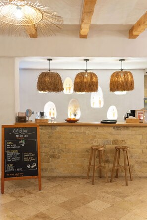 A restaurant interior with a stone counter, three hanging rattan chandeliers, and a chalkboard menu. - 5chirpici (Murighiol)