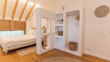 Un dormitorio con cama, vigas de madera, estante empotrado con cestas y un adorno de pared.