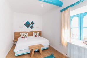 A bedroom with a wooden bed, a small bedside table, a window with curtains, and a wall-mounted light fixture. - 5chirpici (Murighiol)