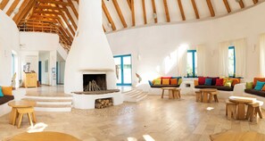 A spacious living area with a central fireplace, wooden furniture, and a staircase leading to an upper level. - 5chirpici (Murighiol)
