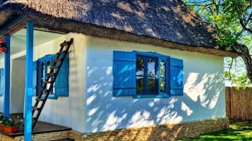 A house with a thatched roof, blue shutters, and a stone foundation.