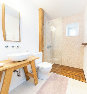 A modern bathroom with a wooden vanity, a large mirror, a white sink, a toilet, and a glass-enclosed shower. - 5chirpici (Murighiol)