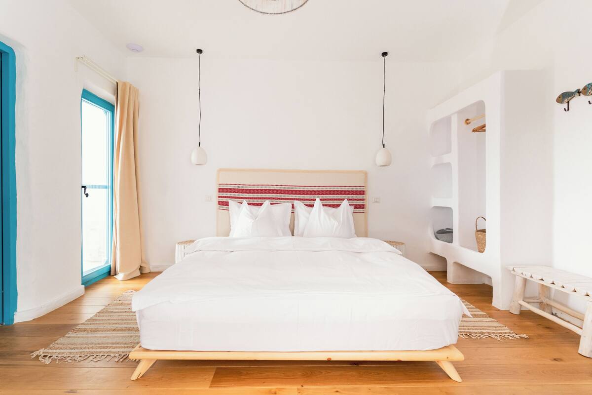 A bedroom with a bed, bedside tables, a window with curtains, and a built-in bench.