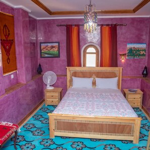 Un dormitorio con cama de madera, candelabro, ventilador y ventana con cortinas.