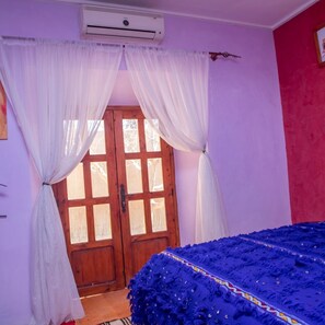 A room with a wooden door, white curtains, and a blue bedspread. - Bassatine Skoura Ouarzazate (Ouarzazate)