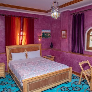 Un dormitorio con una cama de madera, una mesita de noche, una silla, una ventana con cortinas y un candelabro.