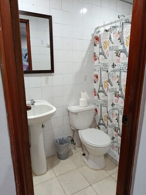 A bathroom with a sink, toilet, and shower curtain. - Hostal Cigarra (Panama City)