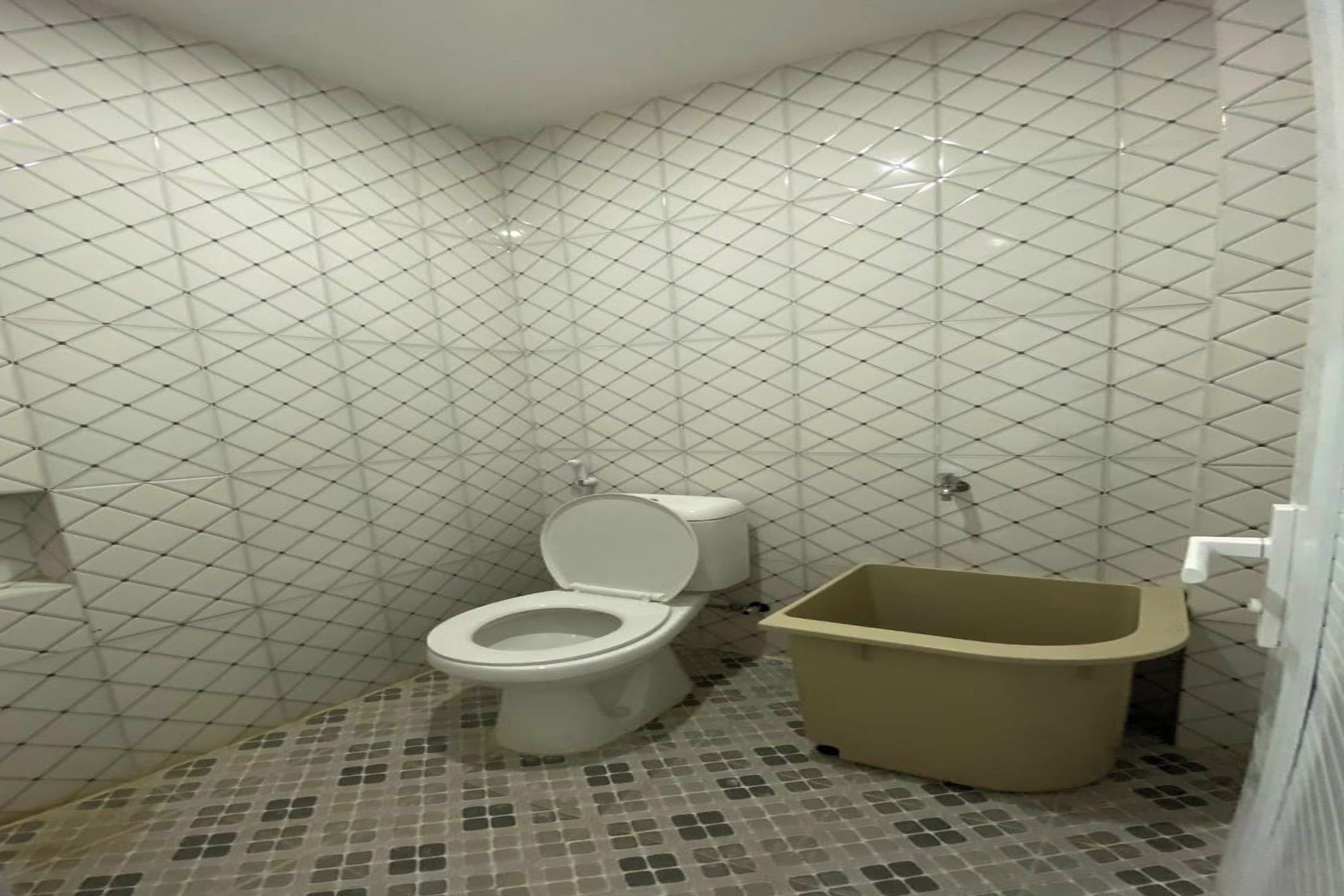 A bathroom with a toilet, a bathtub, and tiled walls.