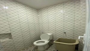 A bathroom with a toilet, bathtub, and tiled walls. - Medina House Syariah By Zuzu (Banda Aceh)
