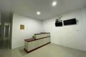 Zona de recepción con mostrador, televisor montado en la pared y aire acondicionado empotrado.