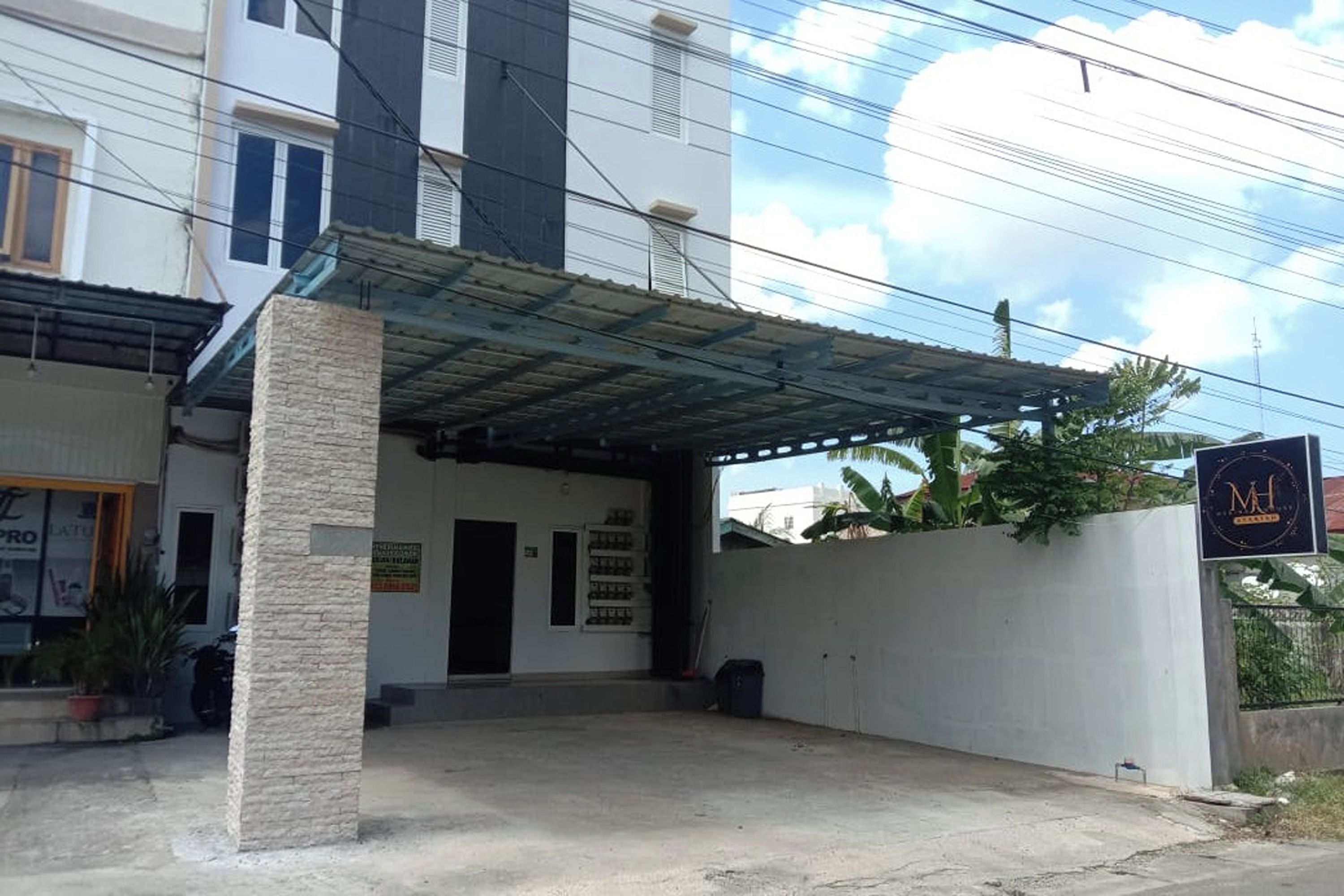 Un edificio con vestíbulo techado, un cartel y una planta en maceta.