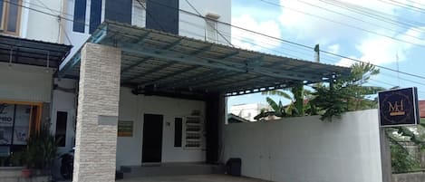 A building with a covered entrance, a signboard, and a potted plant.