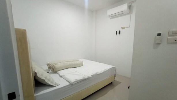 A small, clean room with a single bed, a wall-mounted air conditioner, and a power outlet. - Medina House Syariah By Zuzu (Banda Aceh)