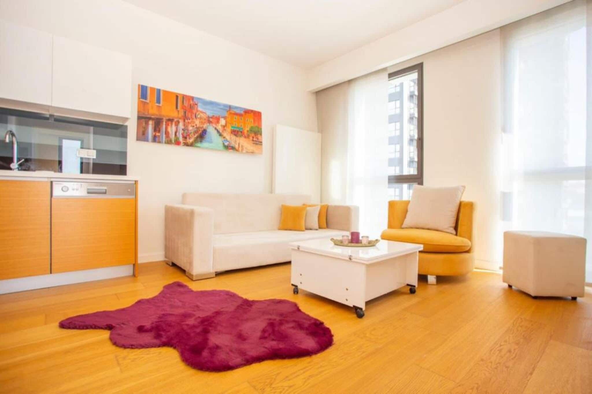 A modern living room with a sofa, armchair, coffee table, and a rug.