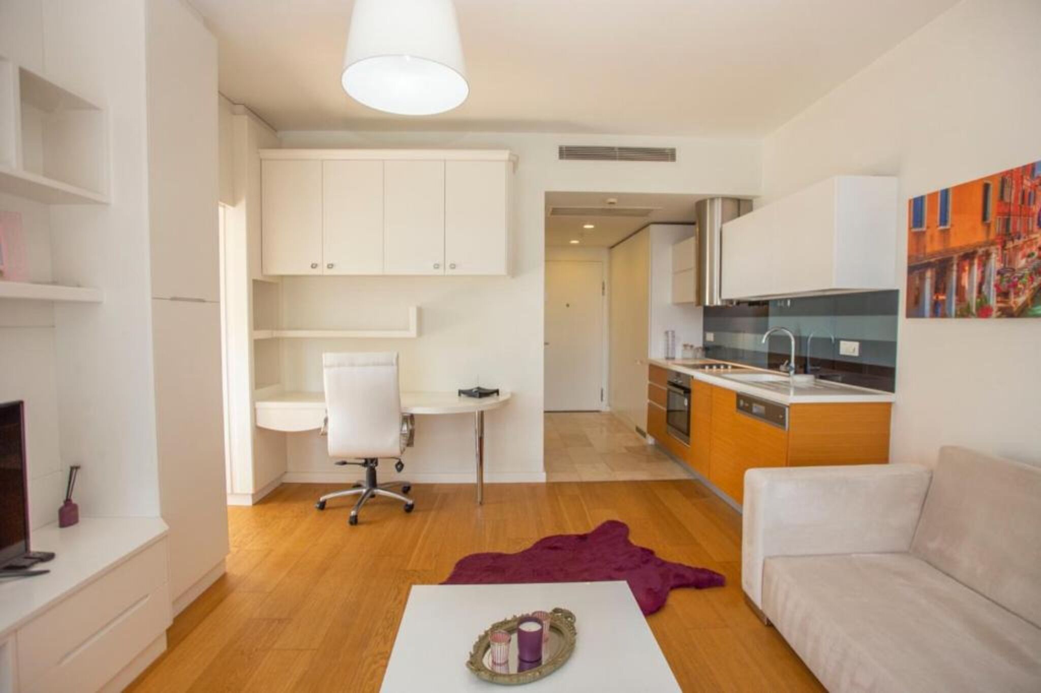A modern apartment with a living room, kitchen, and a small office area.