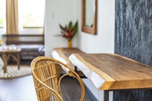 A wooden bench with a white edge, a wicker chair, and a plant in a vase. - Ecotica Boutique Hotel (Quepos)