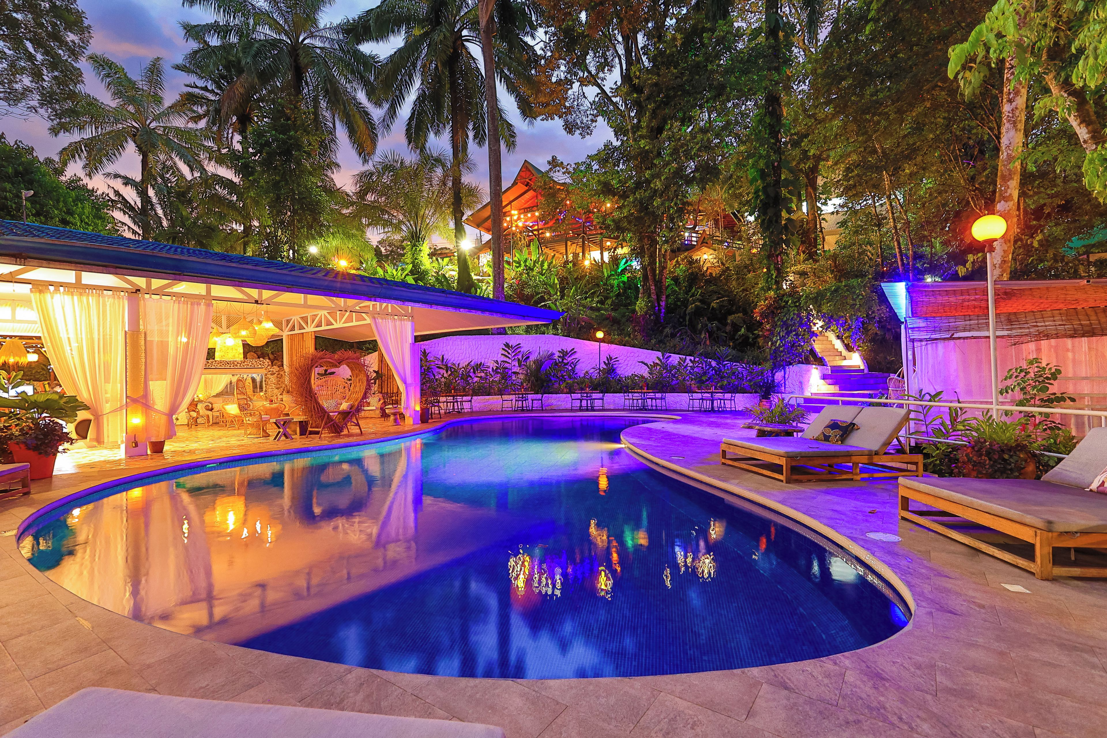 A pool area with lounge chairs and a covered seating area.