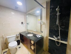 A bathroom with a toilet, sink, vanity, mirror, and shower. - I Lux Hotel Jogja (Ngaglik)