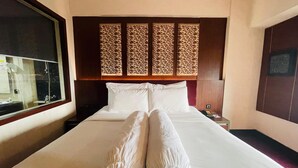 A hotel room with a large bed, a wooden headboard, a nightstand with a phone, and a window with a view. - I Lux Hotel Jogja (Ngaglik)
