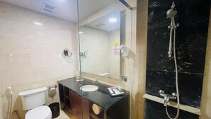 A bathroom with a toilet, sink, vanity, mirror, and shower. - I Lux Hotel Jogja (Ngaglik)
