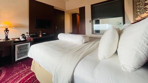 A hotel room with a bed, a television, a desk with a lamp, and a window. - I Lux Hotel Jogja (Ngaglik)