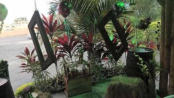 A garden area with various plants and decorative elements, including a wooden structure and a small table.