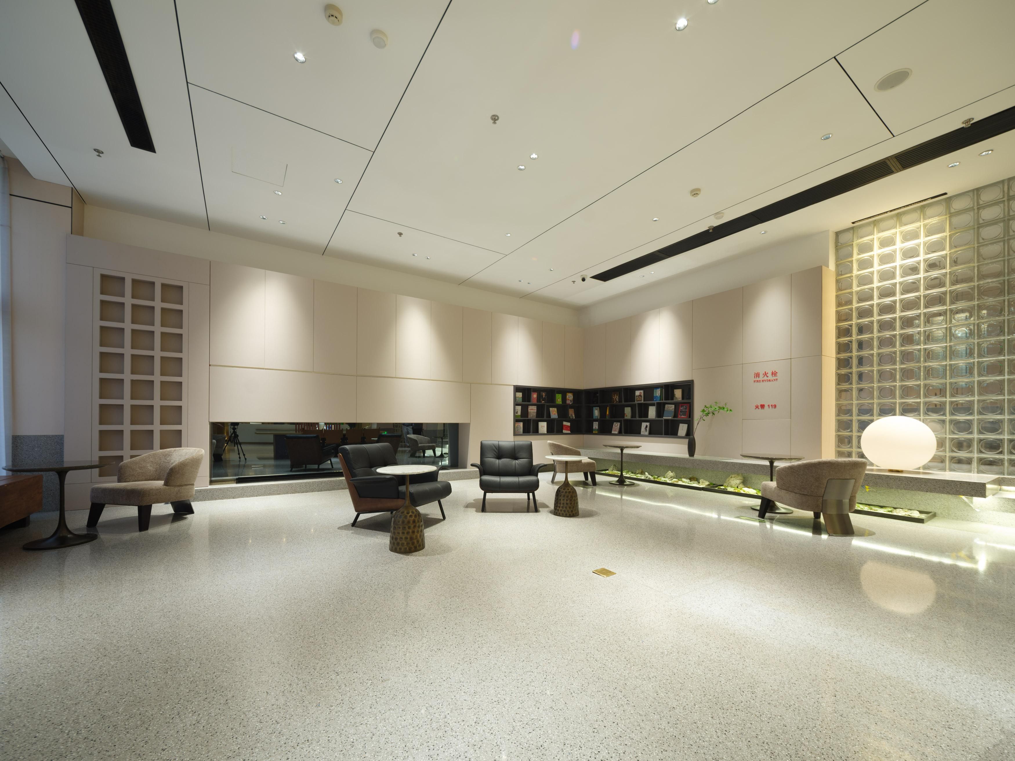 A modern interior with a central seating area, a bookshelf, and a decorative wall.