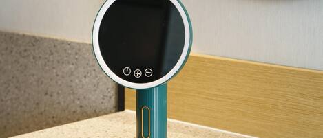 A teal and gold digital mirror with a circular frame, mounted on a textured beige countertop.