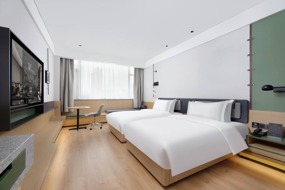 Una habitación de hotel moderna con una cama grande, un escritorio, una silla y una televisión.