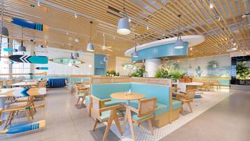 A modern interior with wooden ceiling beams, round tables, and blue seating areas.