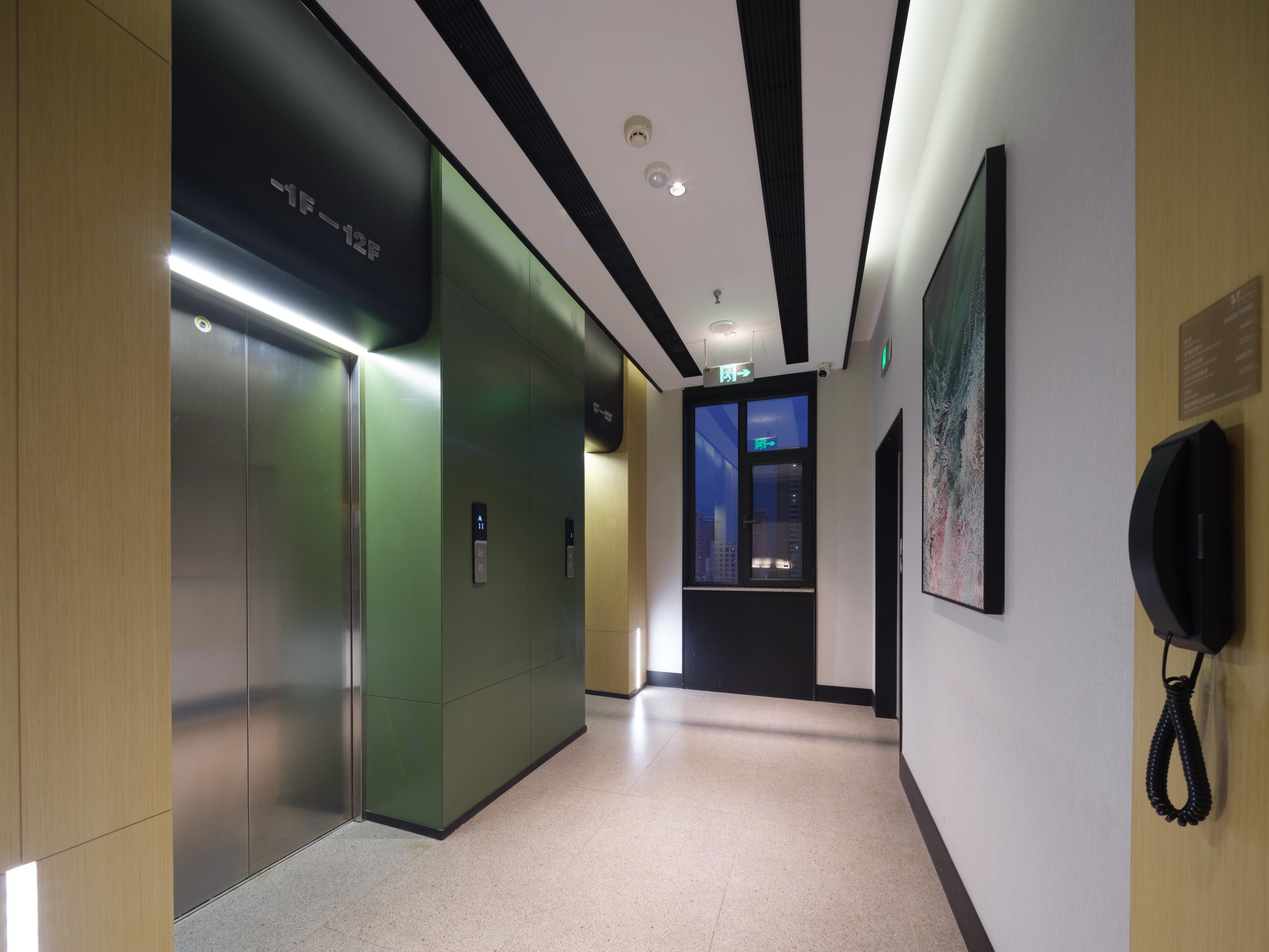 A hallway with an elevator, a telephone, and a wall-mounted sign.