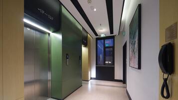 A hallway with an elevator, a telephone, and a wall-mounted sign.
