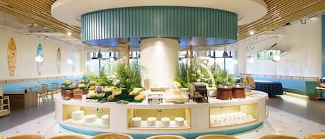 A circular reception area with a central pillar, surrounded by tables and chairs, and a buffet setup.