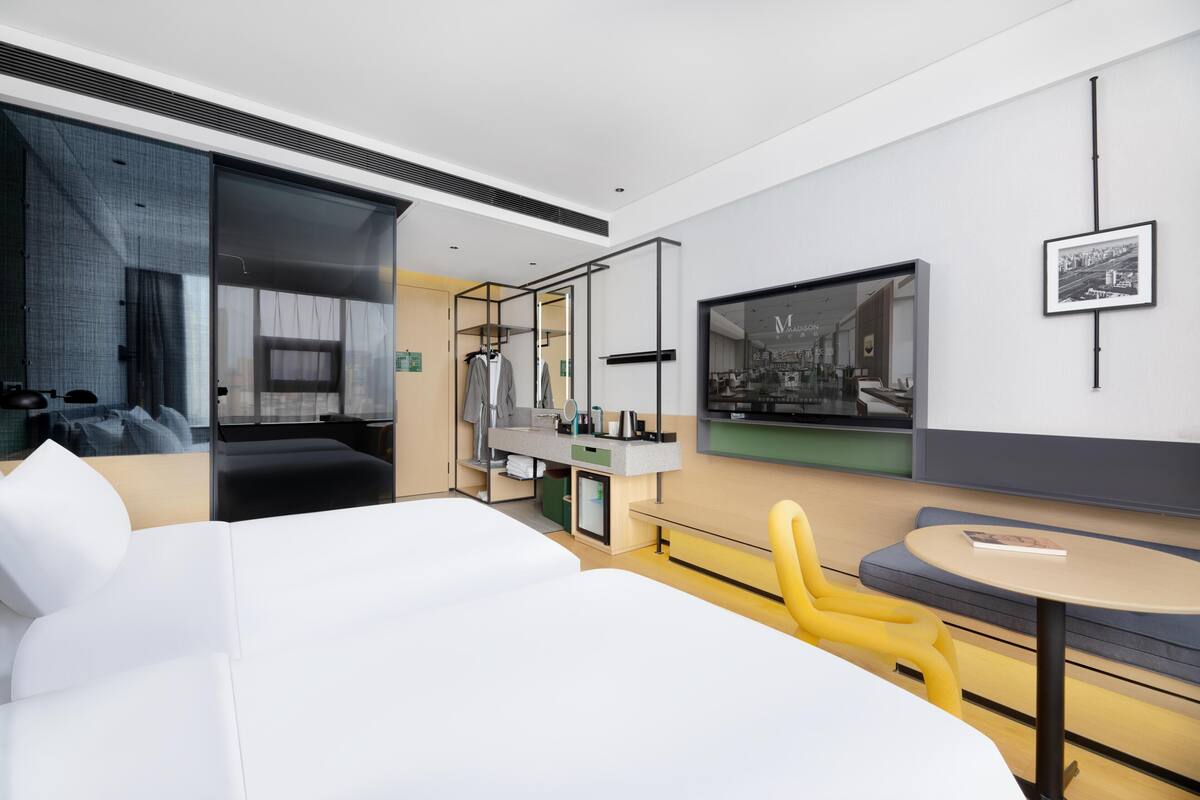 Habitación de hotel moderna con una cama grande, un área de descanso con una mesa redonda, un televisor y un armario.