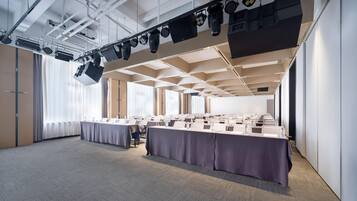 A conference room with a long table, ceiling-mounted lighting, and a carpeted floor.