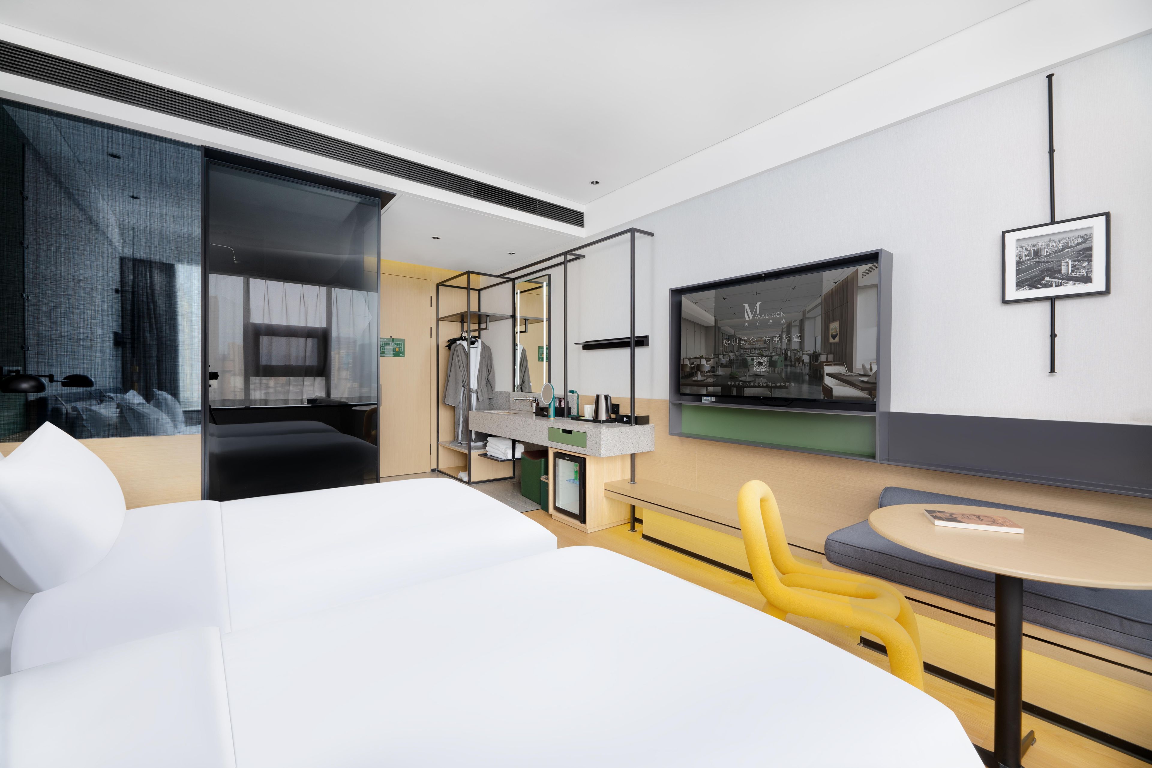 Una habitació d'hotel moderna amb un llit gran, una zona de seients amb una taula rodona, un televisor i un armari.